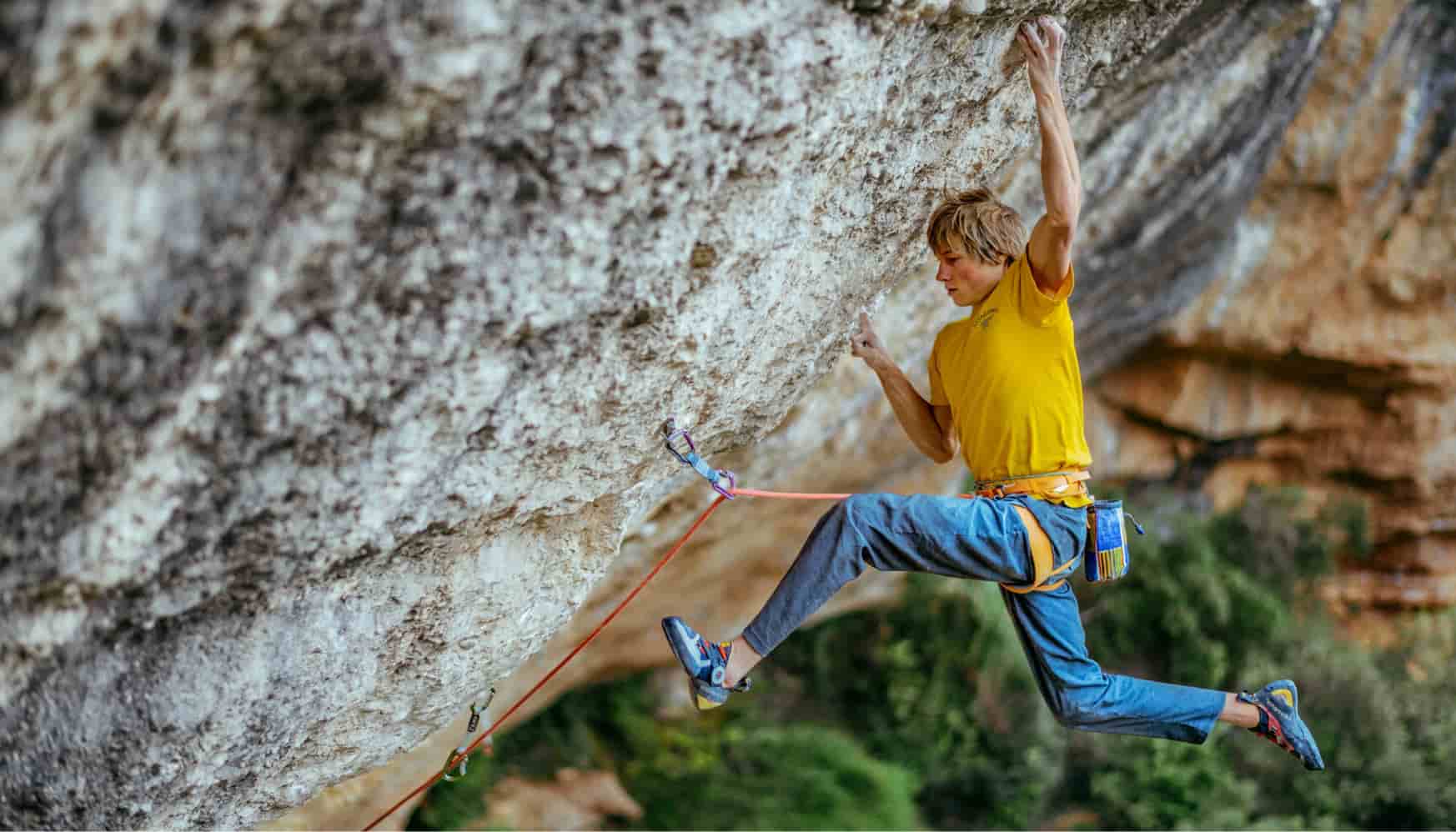 Man in yellow t-shirt climbing a mountain